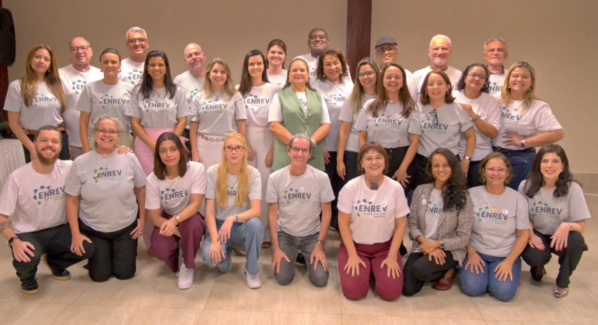 Voluntários e voluntárias da Rede +Voz reunidos no Encontro Nacional, vestindo camisetas do ENREV